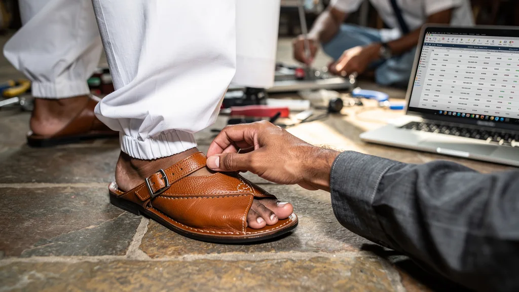 Click to manage / replace image A pair of traditional brown leather Peshawari chappals worn with a white pajama.