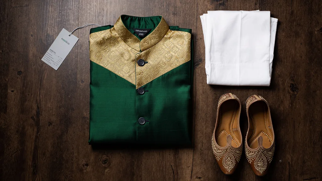 Click to manage / replace image A curated flat lay of a Nehru jacket, silk kurta, and churidar pants.